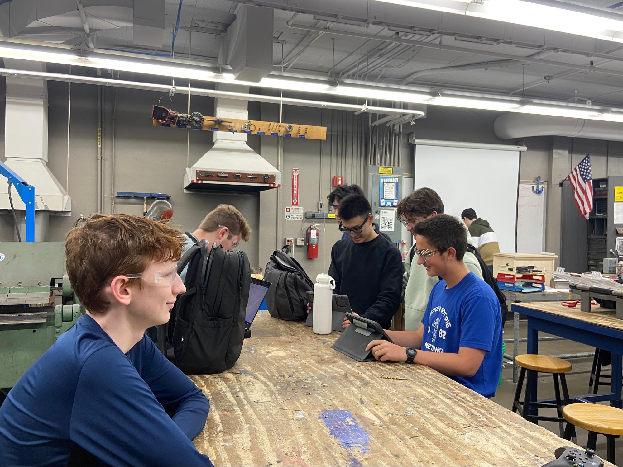 The strategy team working on their devices in the metal shop